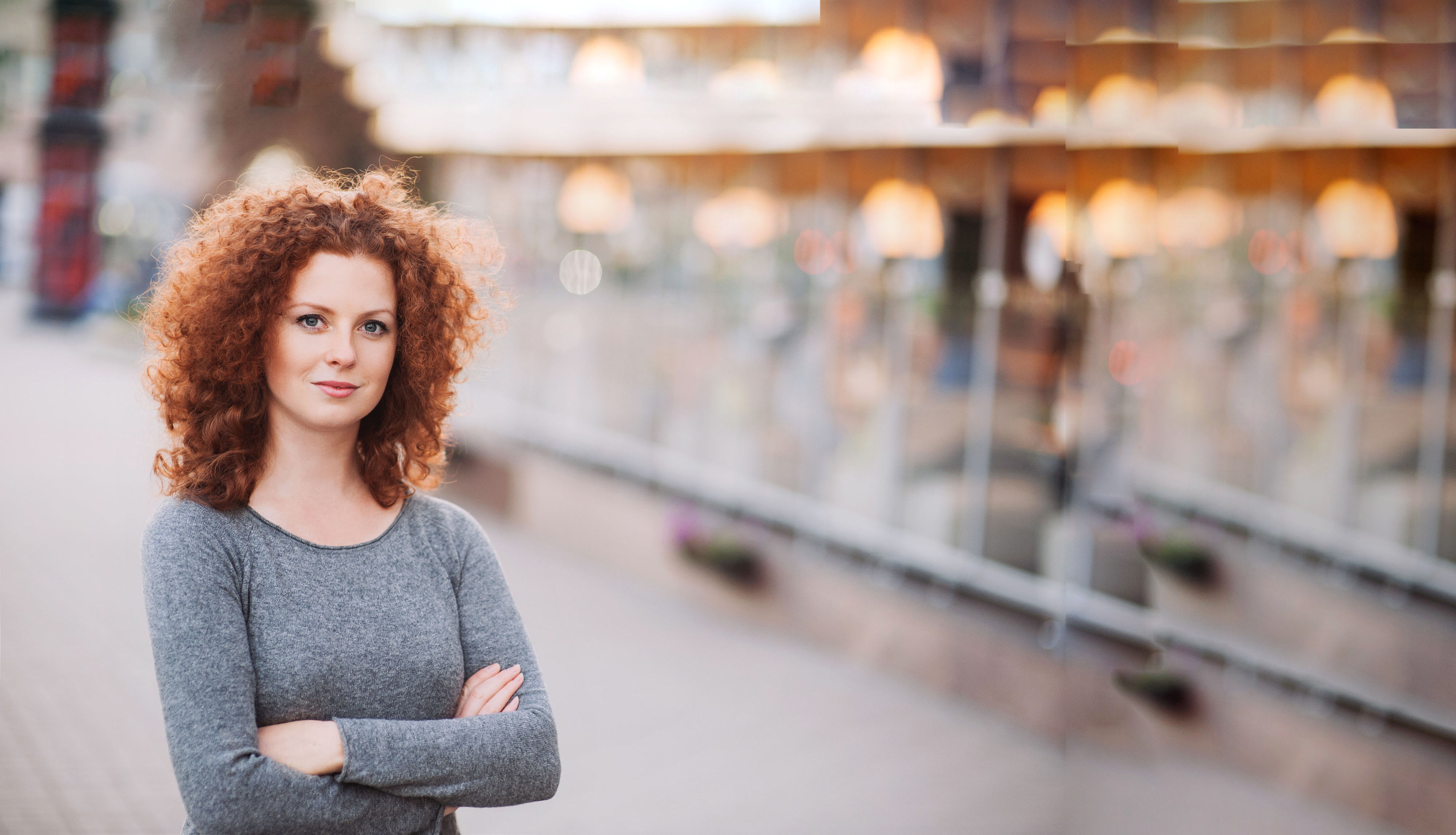 Lady with arms crossed standing to the left of a glass partition wall